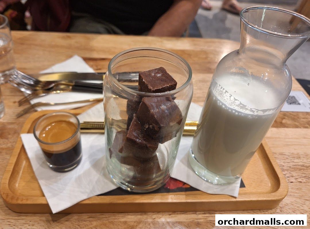 A serving of espresso, chocolate cubes, and milk on a wooden tray.