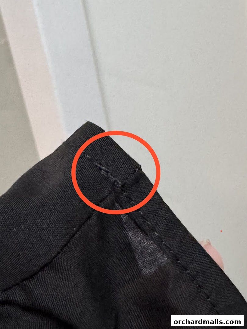 Close-up of black fabric with stitching and a red circle highlighting a detail.