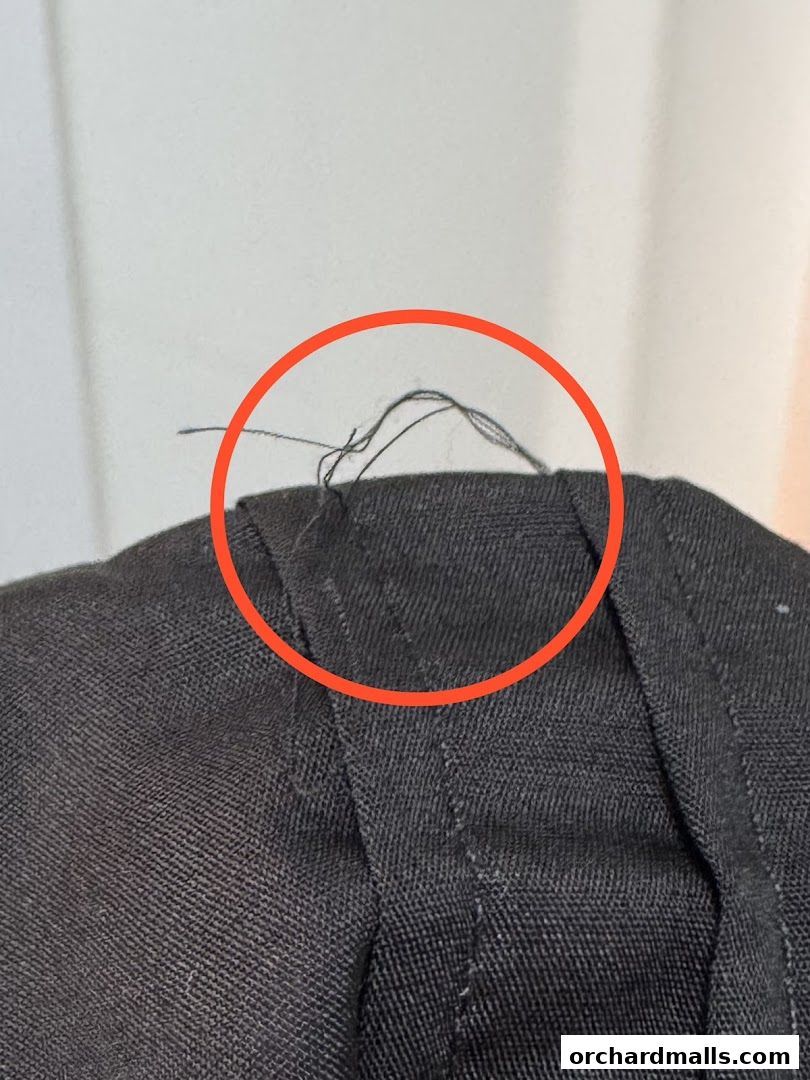 Close-up of loose threads on dark fabric, highlighted by a red circle.