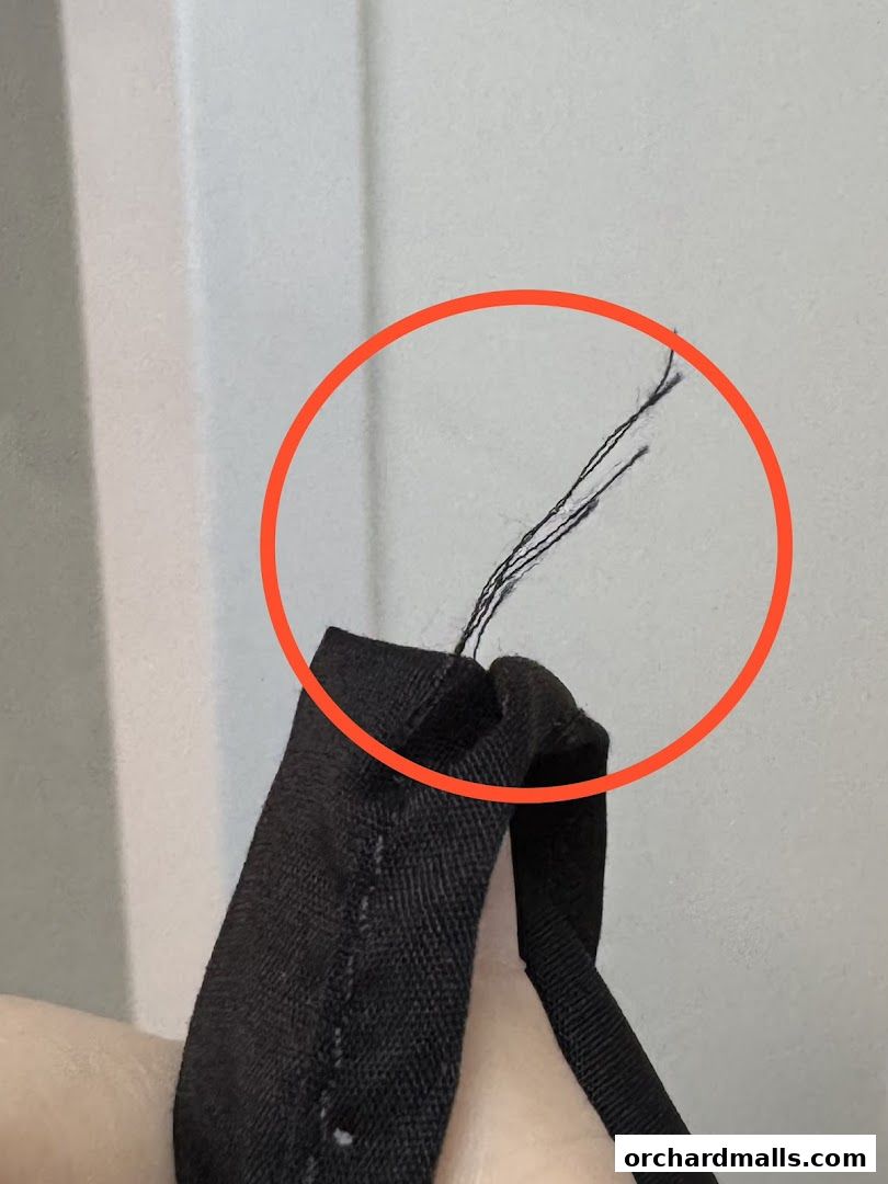 Close-up of loose threads on a black fabric item, highlighted by a red circle.