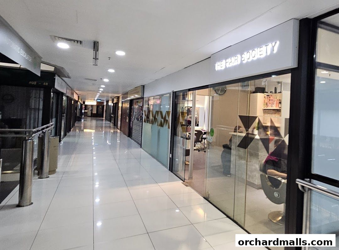 Exterior view of 'The Hair Society' salon in a shopping mall corridor.