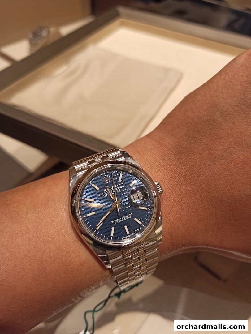 A close-up of a Rolex watch with a blue dial on a person's wrist.