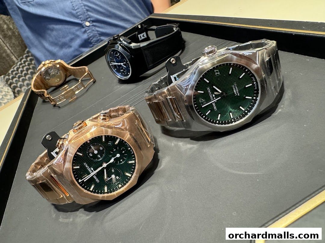 A display of luxury watches, including Girard-Perregaux models, on a dark tray.
