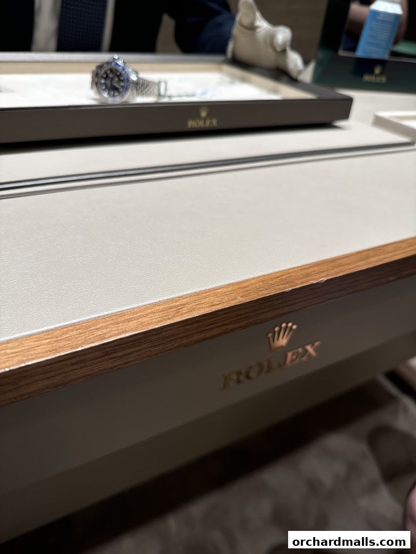 A close-up of a Rolex watch displayed in a luxury retail setting.