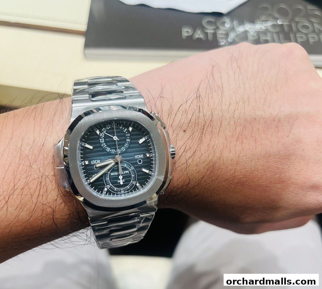 A close-up of a Patek Philippe watch on a wrist, with a catalog in the background.