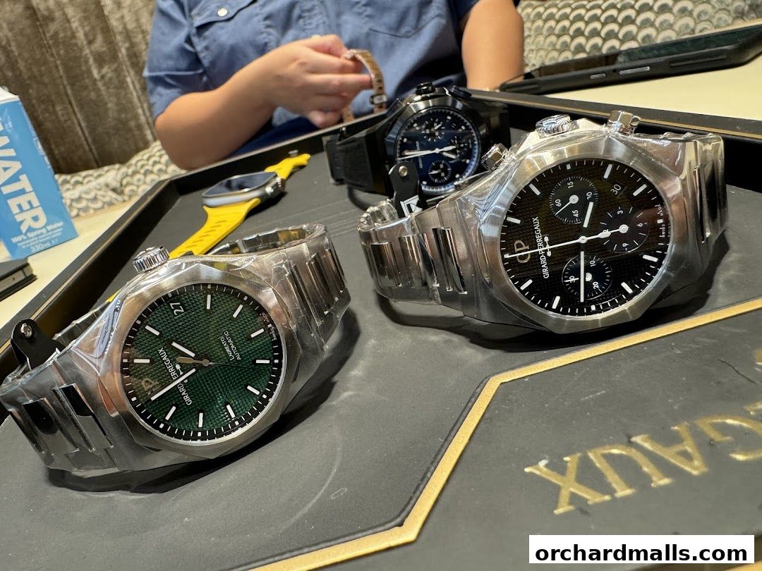 Luxury watches from Girard-Perregaux displayed on a tray with a person in the background.