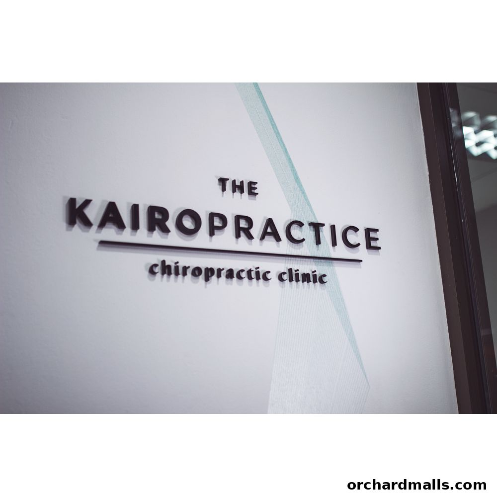 The KAIRO Practice Chiropractic Clinic sign on a white wall with a subtle design.