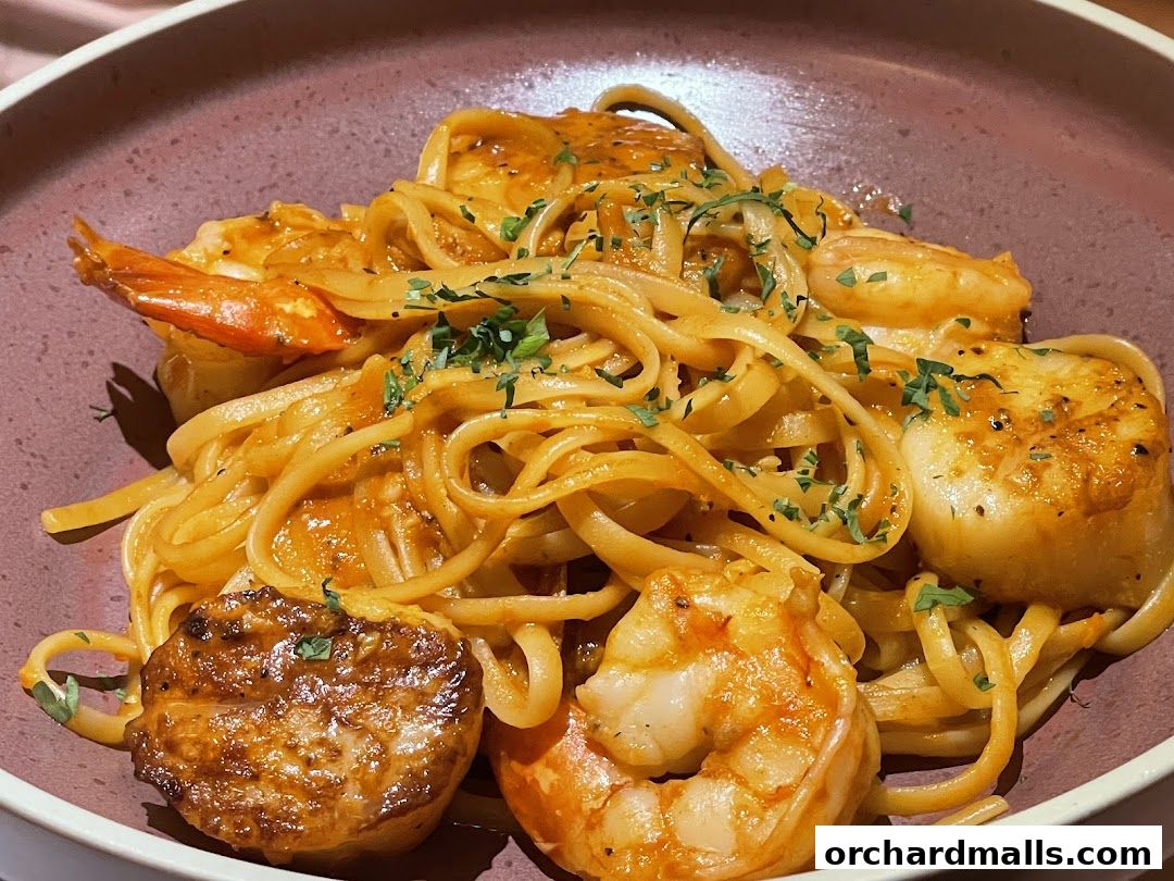 A close-up of linguine pasta with shrimp and scallops in a rich sauce.