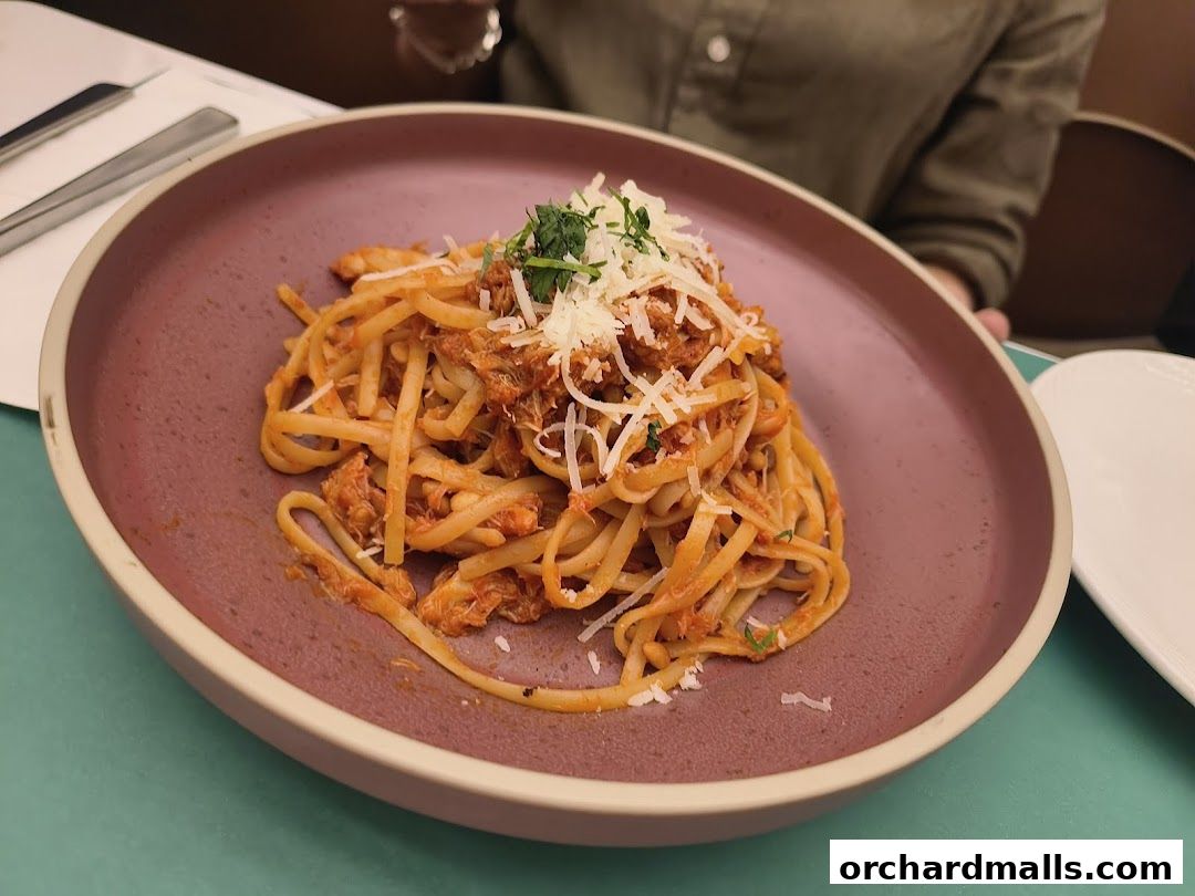 A close-up of a delicious pasta dish with shredded meat and cheese on a purple plate.