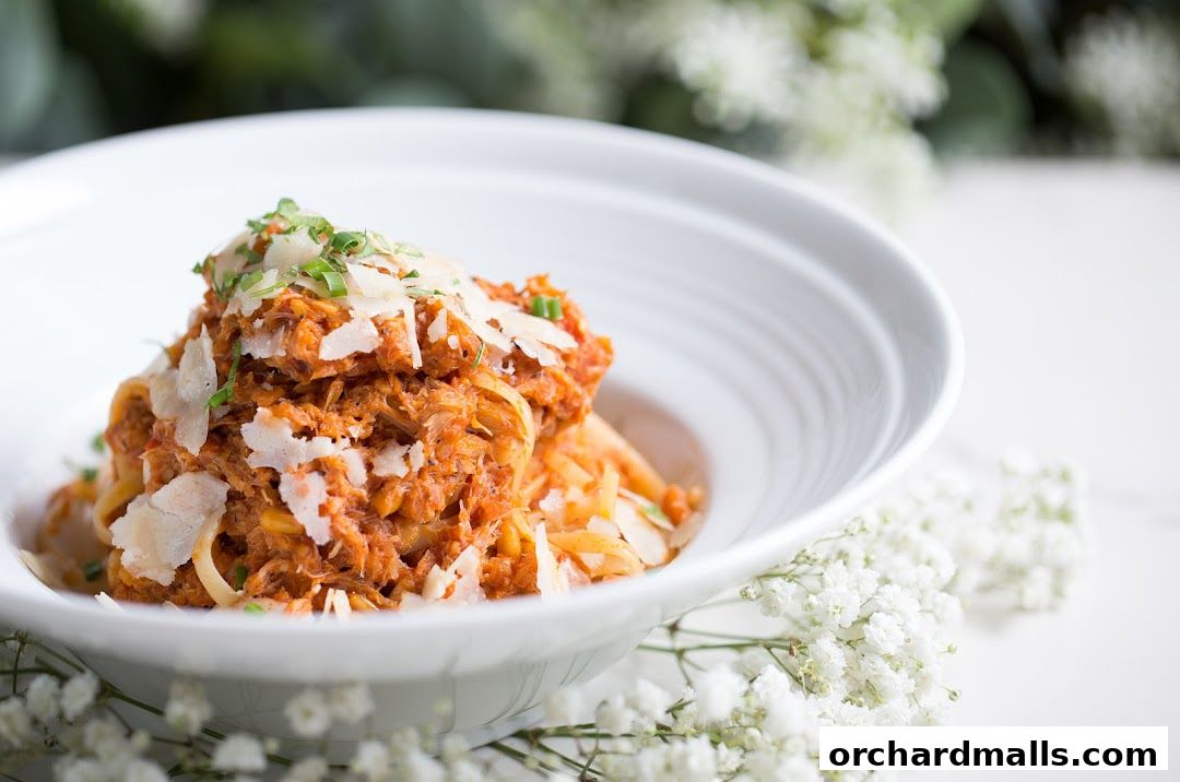 A close-up of a delicious pasta dish topped with shredded meat and cheese.