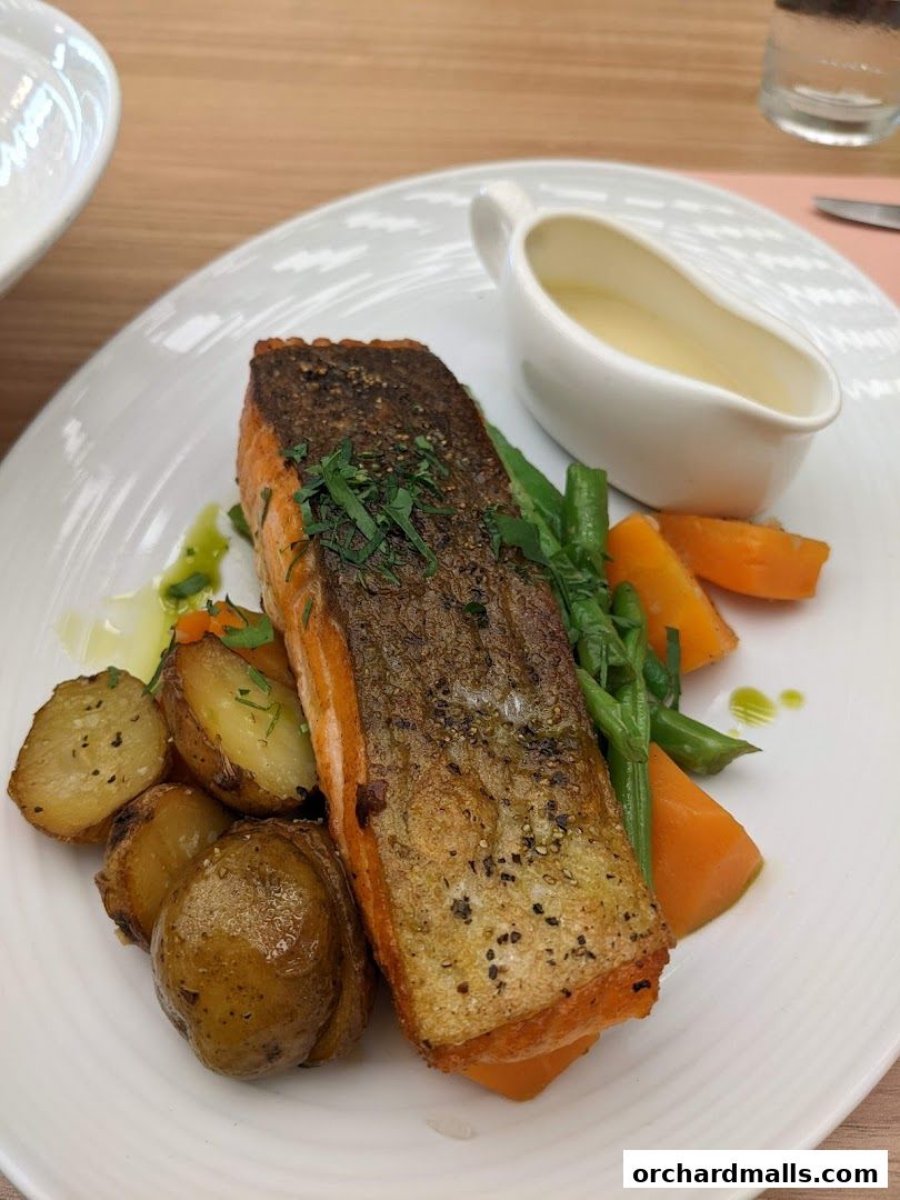 A close-up of a perfectly cooked salmon fillet with roasted potatoes and vegetables.