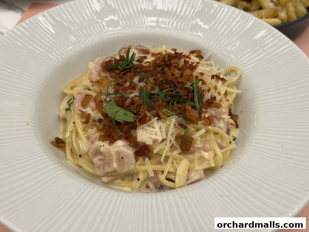 A close-up shot of a delicious spaghetti carbonara dish served in a white bowl.