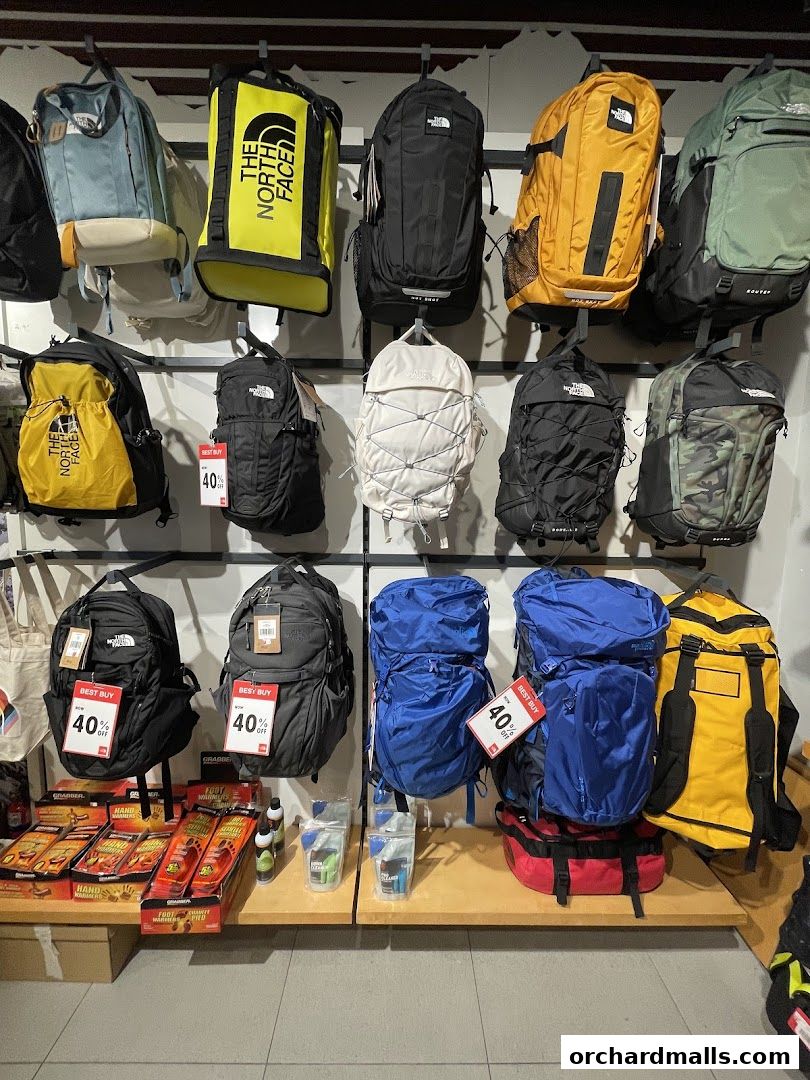 A wall display of various North Face backpacks in different colors and styles, with some promotional tags.