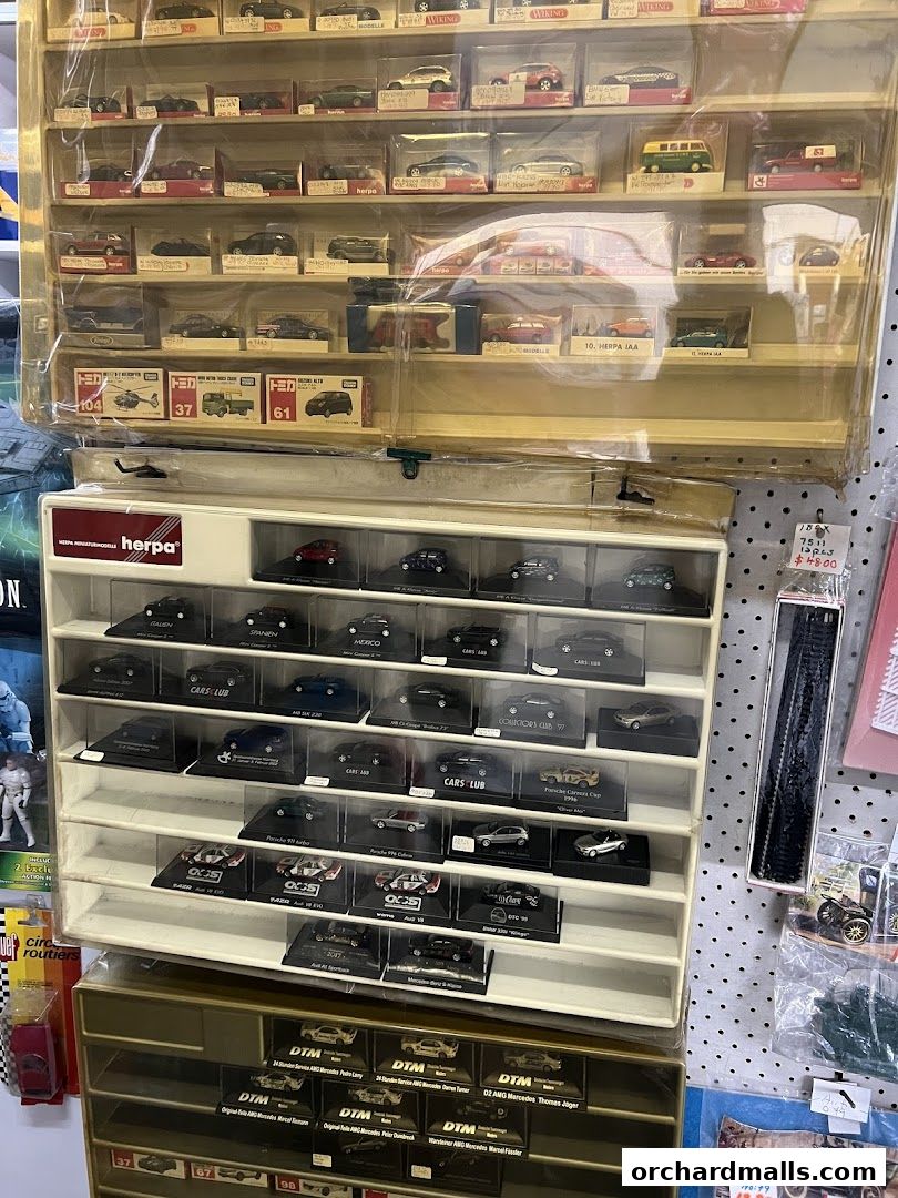 A display of various collectible model cars in clear plastic cases on shelves.