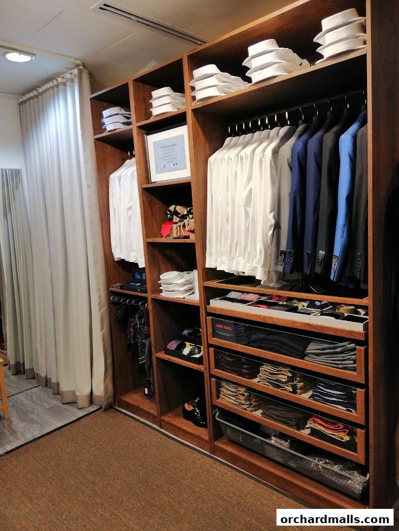 A well-organized display of men's shirts, suits, ties, and accessories in a retail store.