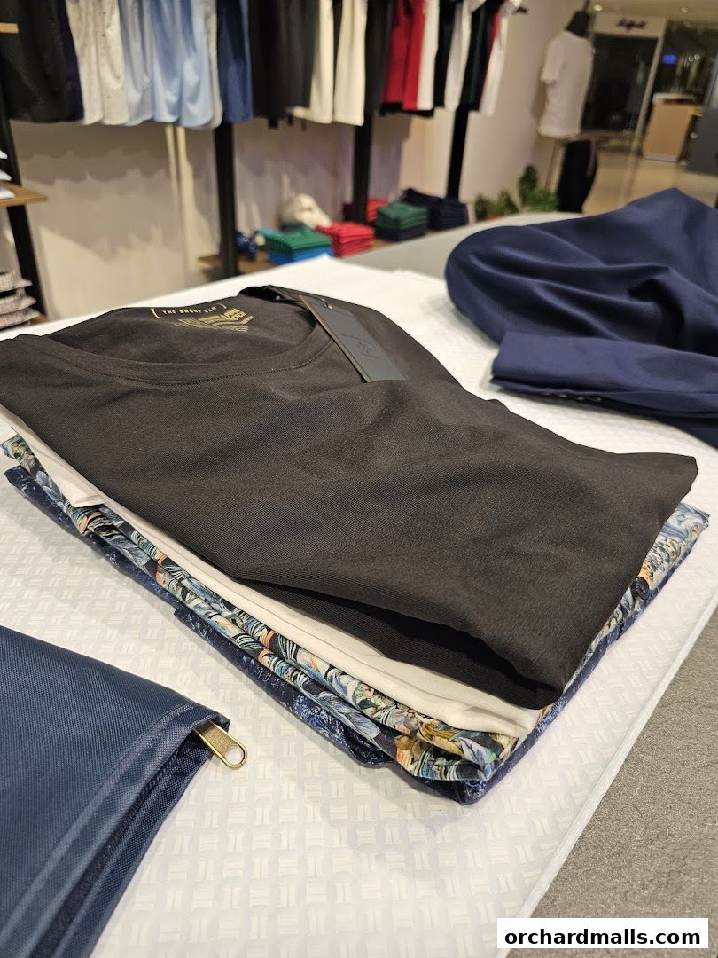 Neatly folded t-shirts and patterned fabrics displayed on a white surface.
