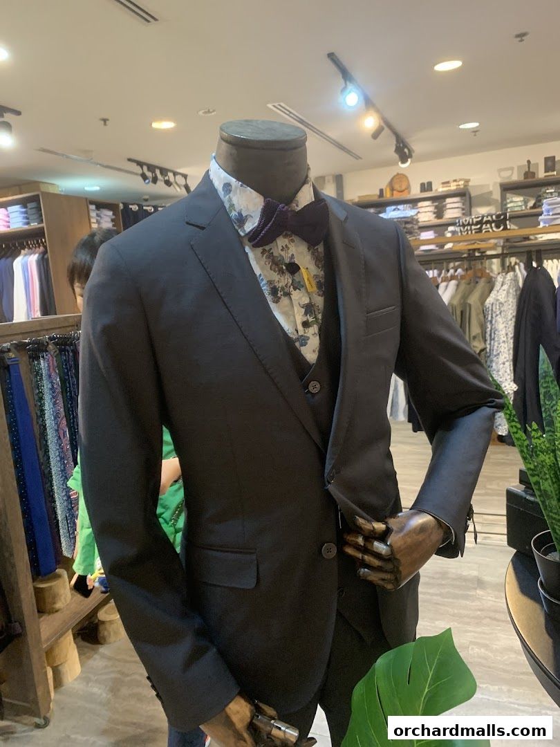 Mannequin dressed in a dark suit, patterned shirt, and bow tie at The Shirt Bar.