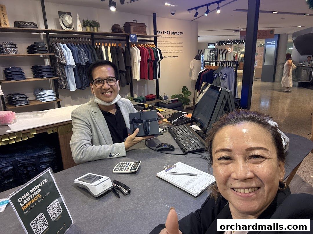 Two smiling people in a clothing store, one holding a gift box.