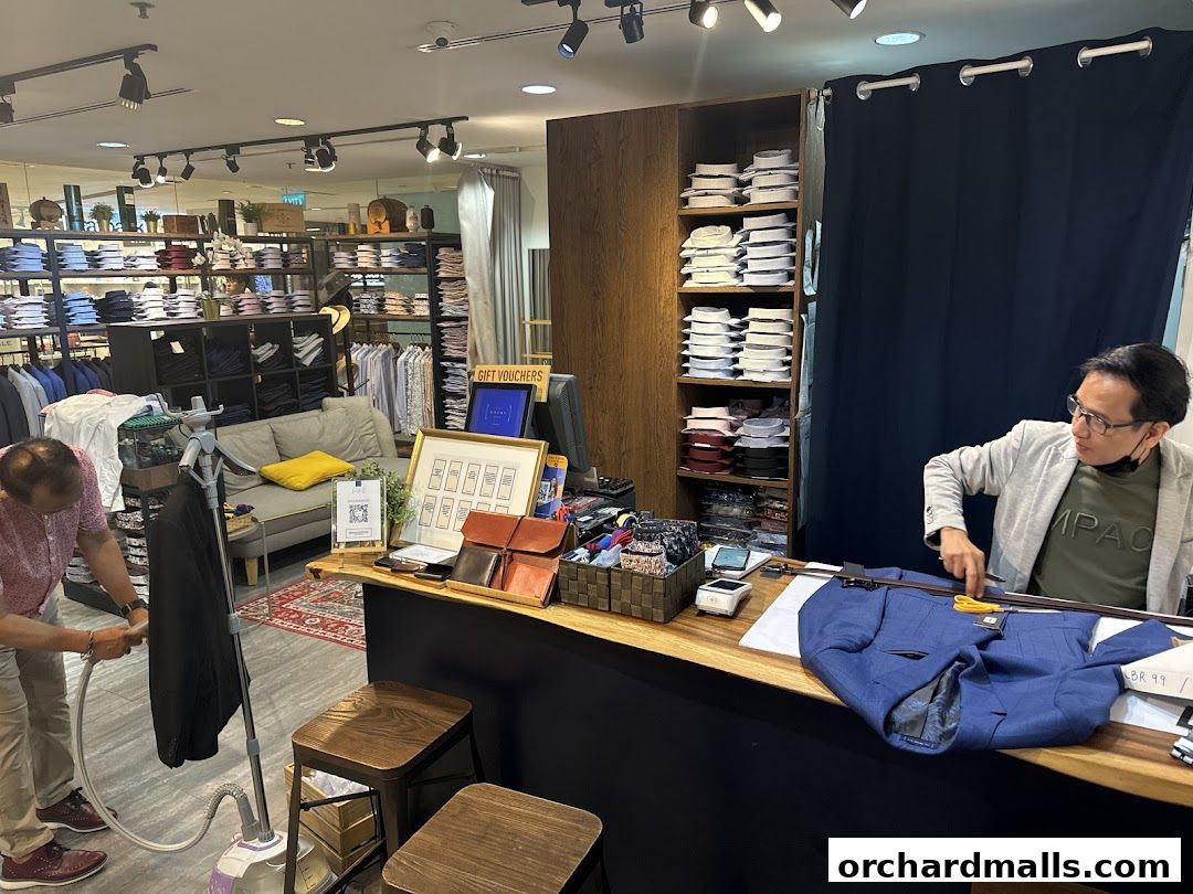 A tailor steams a suit jacket in a well-stocked shirt and tailoring shop.