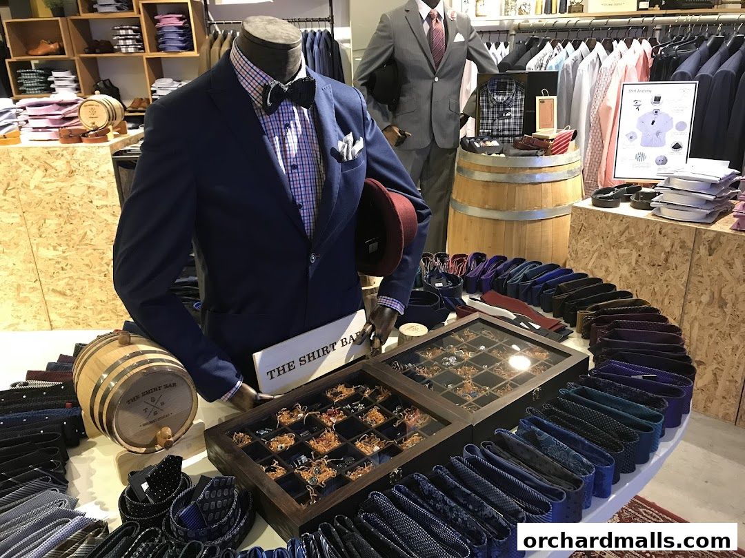 Mannequins display suits and accessories, with ties and cufflinks arranged on a table.