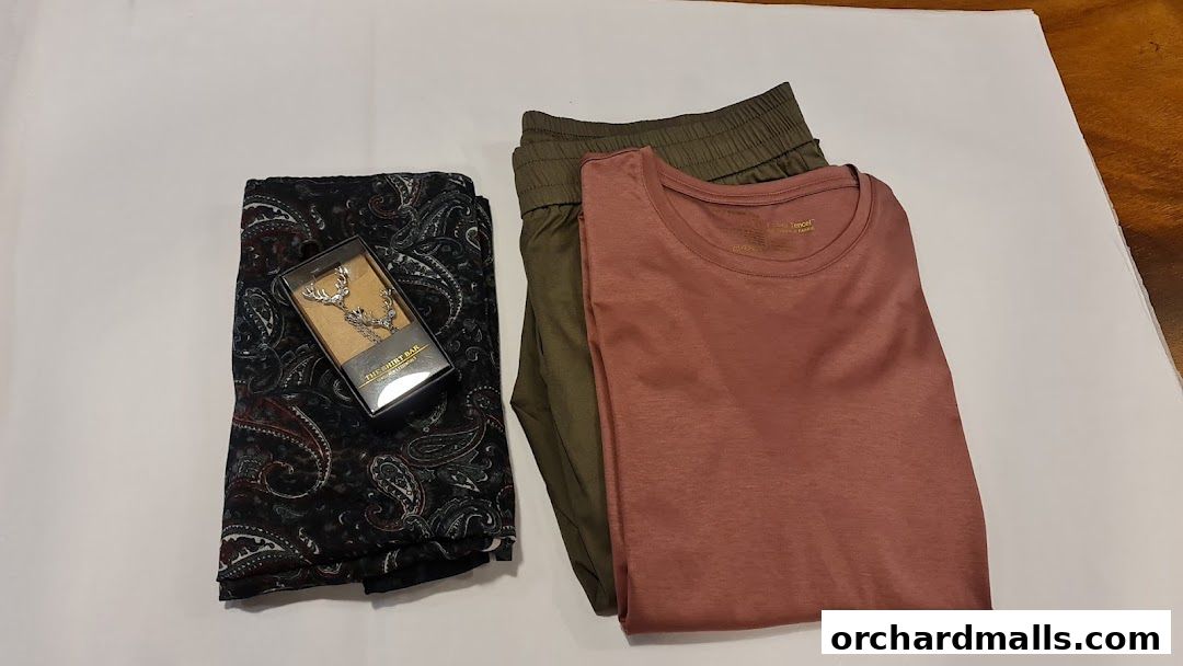 A paisley scarf, deer antler cufflinks, and casual apparel laid out on a white surface.