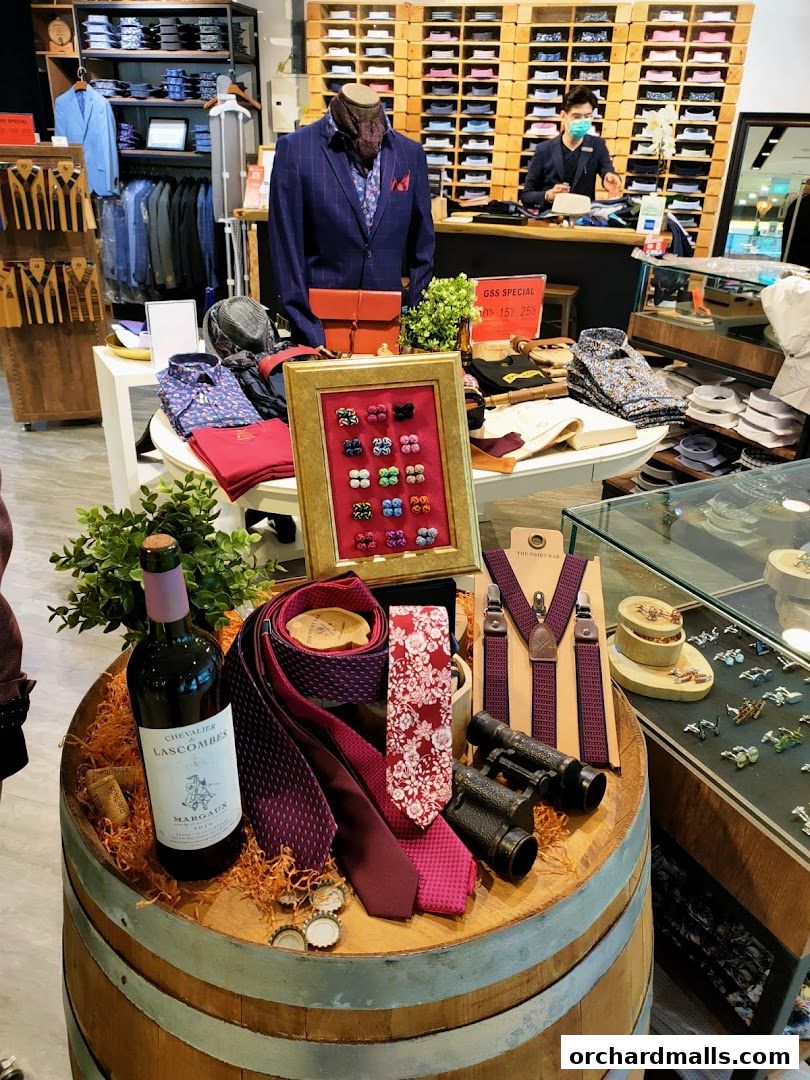A display of men's accessories including ties, cufflinks, suspenders, and a bottle of wine.