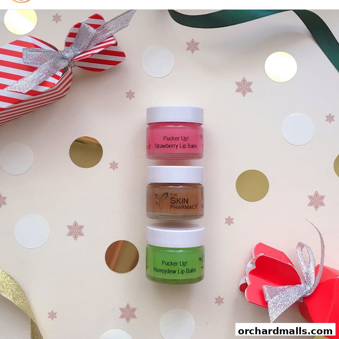 Three small jars of lip balm from The Skin Pharmacy, arranged with festive decorations.