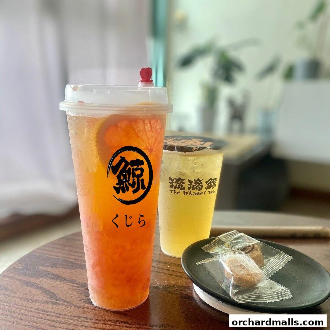 Two refreshing fruit teas and two small cookies on a wooden table.