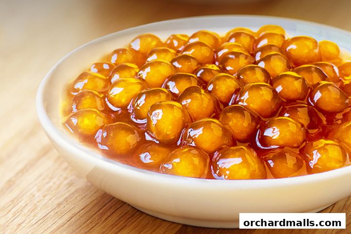 A close-up shot of golden boba pearls in a white bowl on a wooden surface.