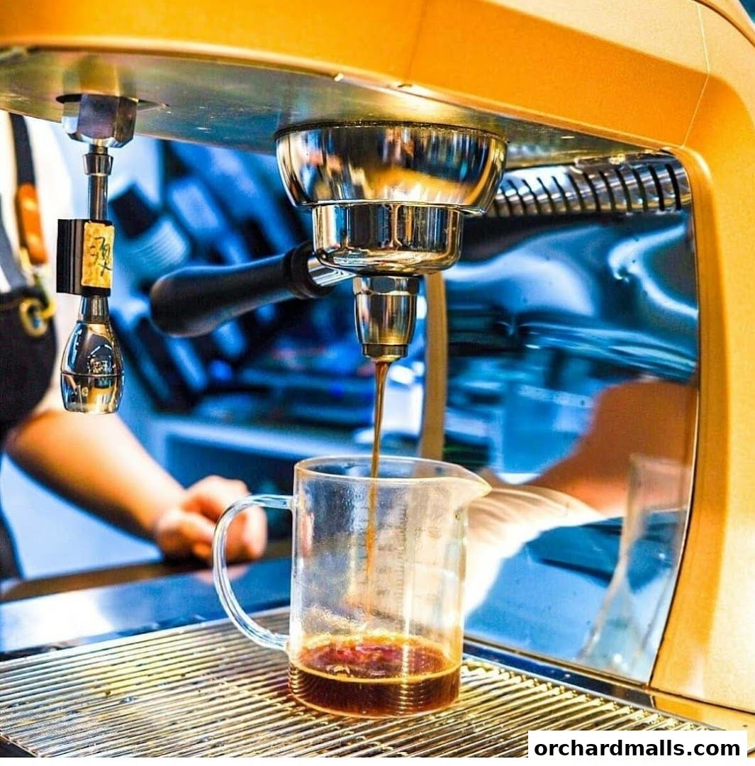 Espresso being brewed from a machine into a glass pitcher.
