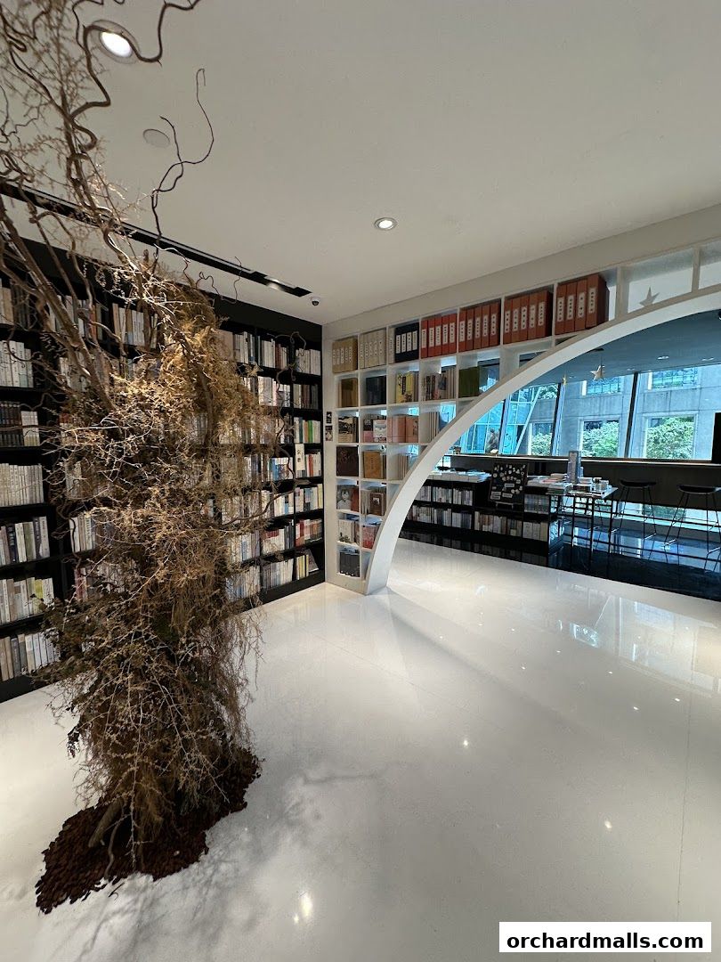 Interior of a modern bookstore with bookshelves, a unique tree installation, and seating area.