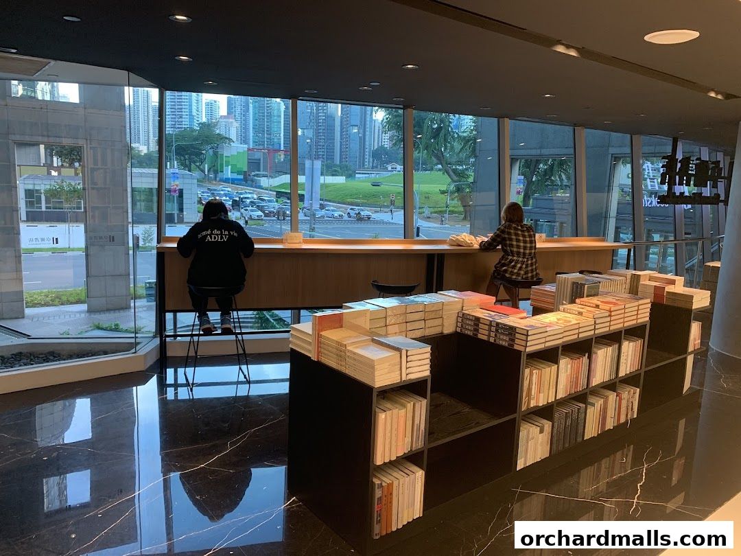 Interior of a modern bookstore with shelves of books and people sitting at a counter.
