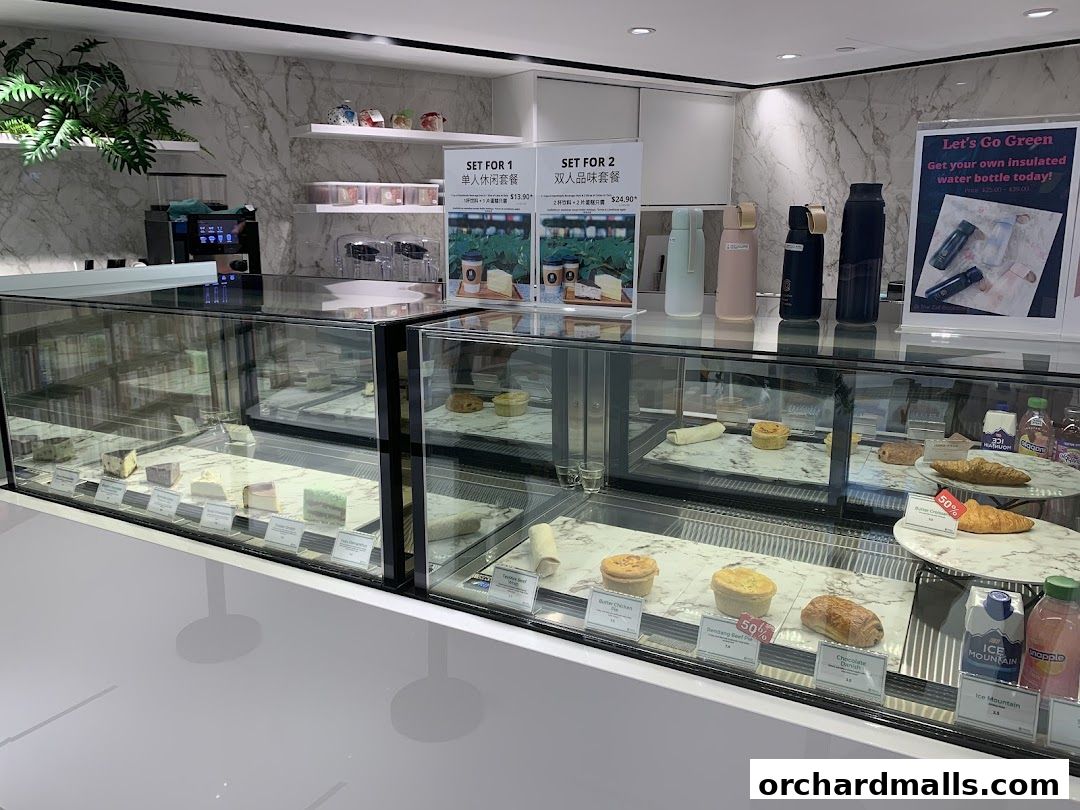 A display of pastries and drinks in a modern cafe setting with promotional signs.