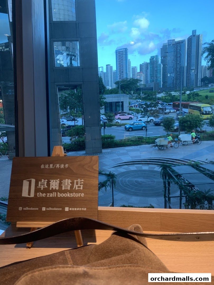A sign for The Zall Bookstore with a city skyline view through the window.