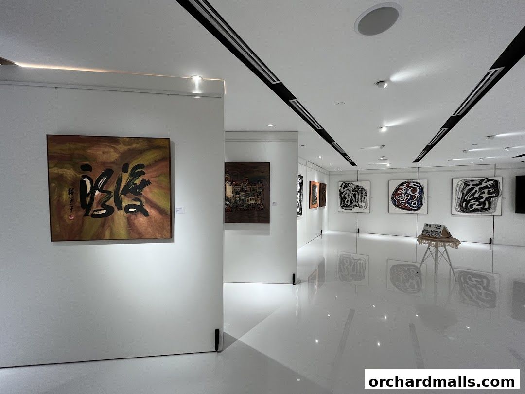 Interior view of a modern art gallery with various paintings displayed on white walls.