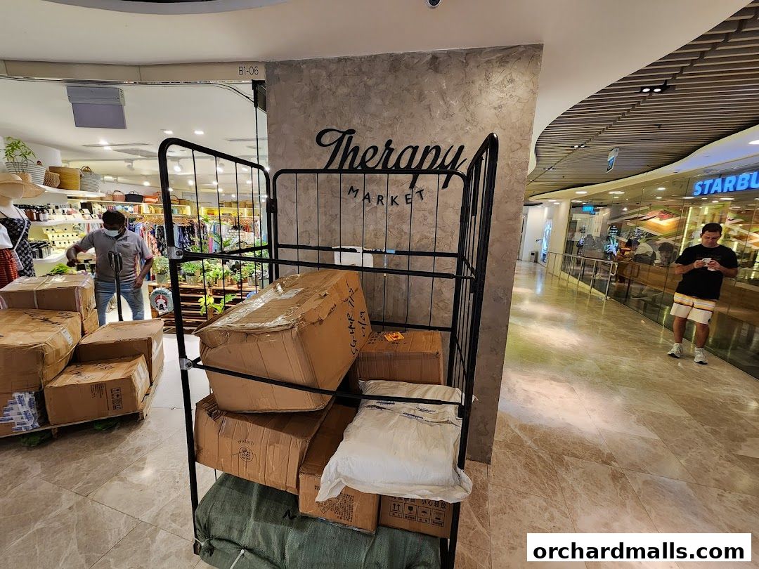 A man is unloading boxes in front of the Therapy Market shop.
