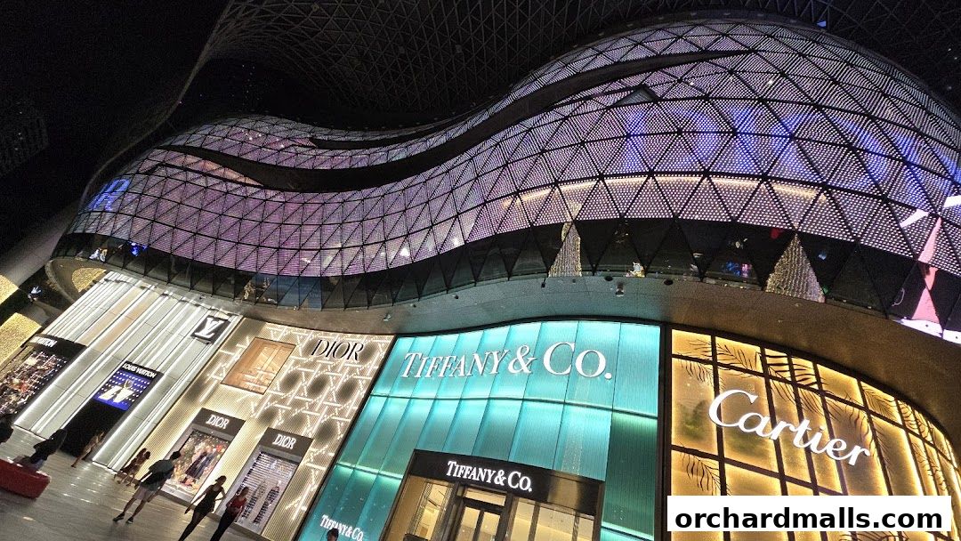 Exterior view of luxury brand stores including Tiffany & Co., Dior, Louis Vuitton, and Cartier at night.