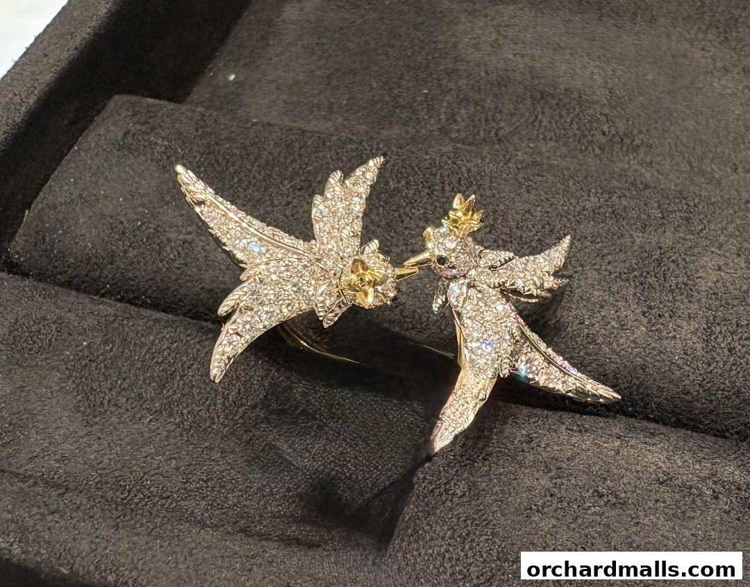 A close-up of a sparkling diamond-encrusted brooch shaped like two birds.