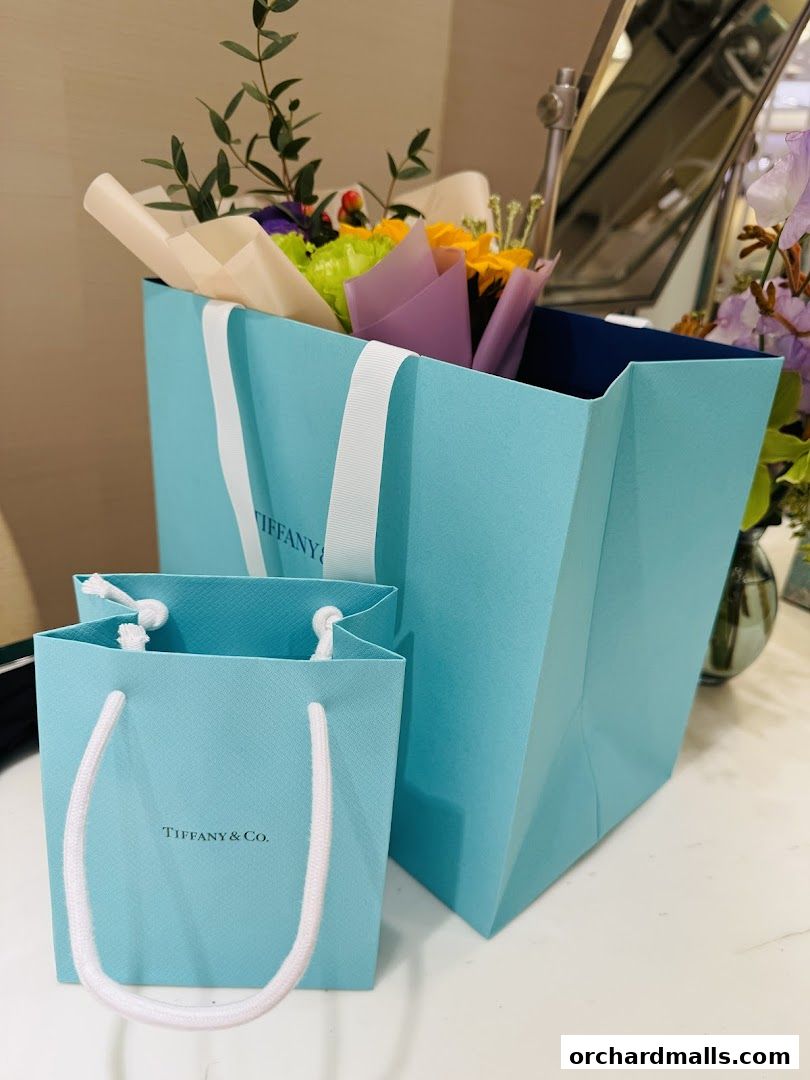 Tiffany & Co. shopping bags with flowers inside, suggesting a gift.