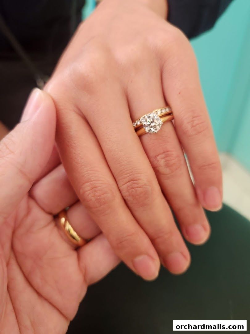 Close-up of hands wearing Tiffany & Co. engagement and wedding rings.