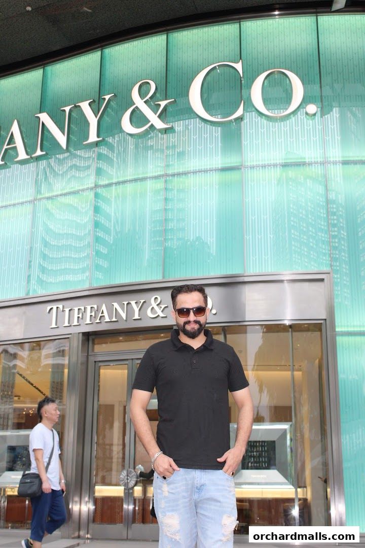 A man stands in front of the Tiffany & Co. store entrance with its iconic signage.