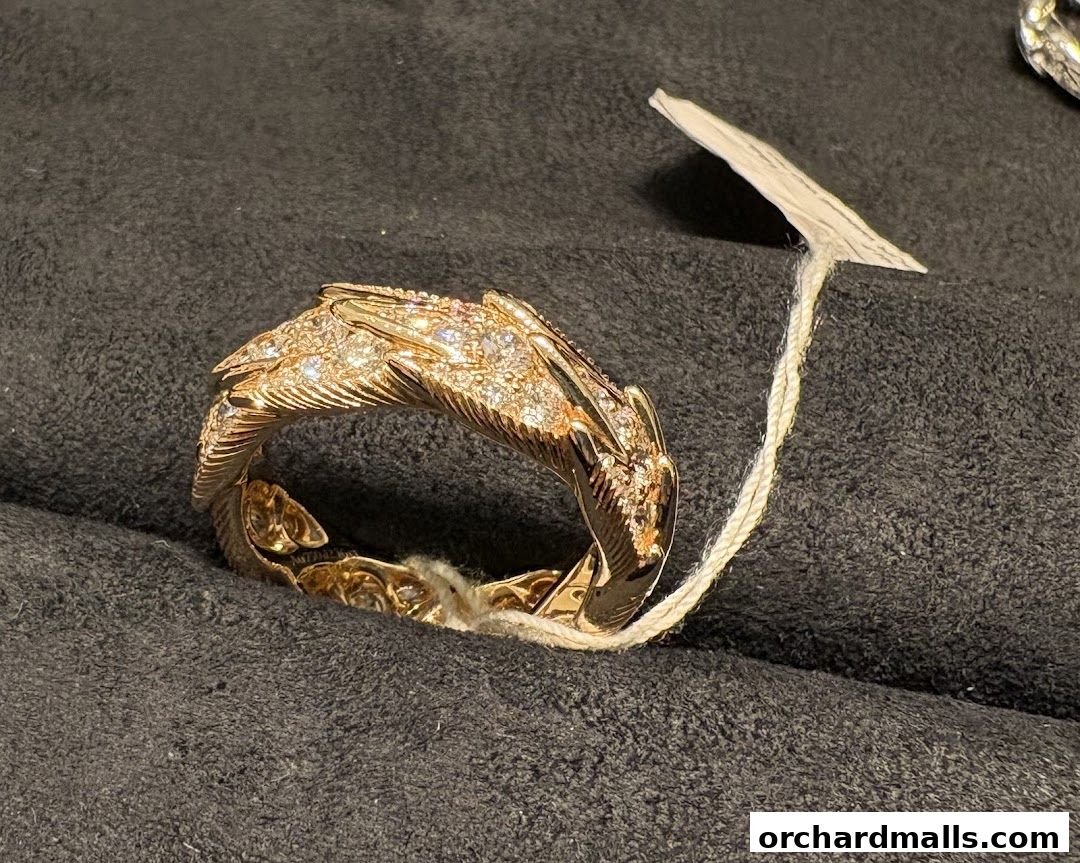 A close-up of a diamond-encrusted dragon-shaped ring on a dark, textured surface.