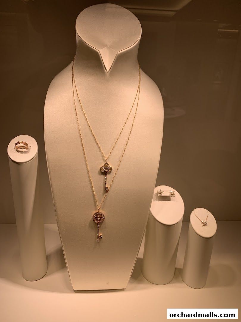 A display of elegant Tiffany & Co. necklaces, earrings, and a ring in a shop window.