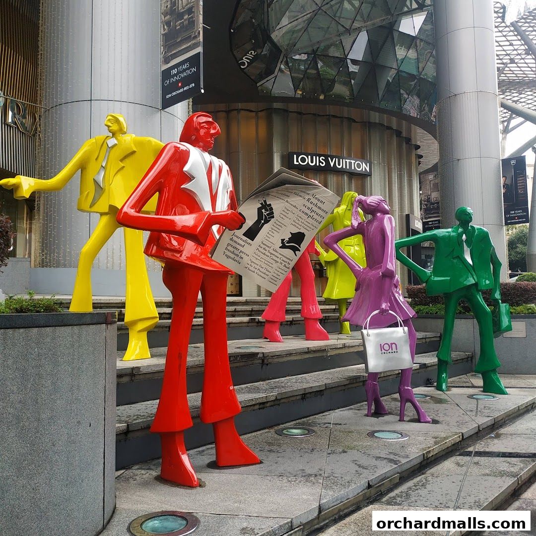 Colorful sculptures of people reading a newspaper and carrying shopping bags outside a Louis Vuitton store.