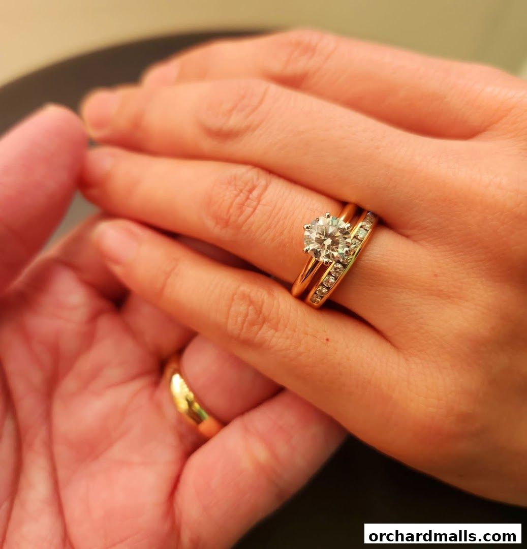 Close-up of hands wearing Tiffany & Co. diamond engagement and wedding rings.