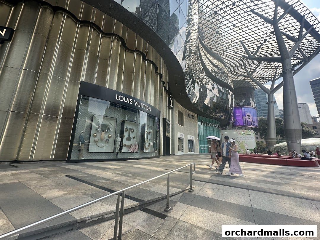 A Louis Vuitton store front with a display window and people walking by.