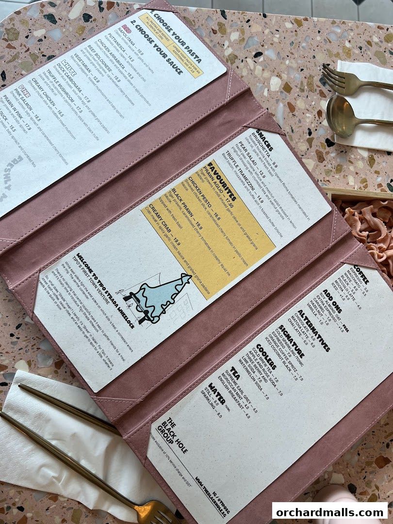 A pink menu open on a terrazzo table, displaying pasta and drink options.