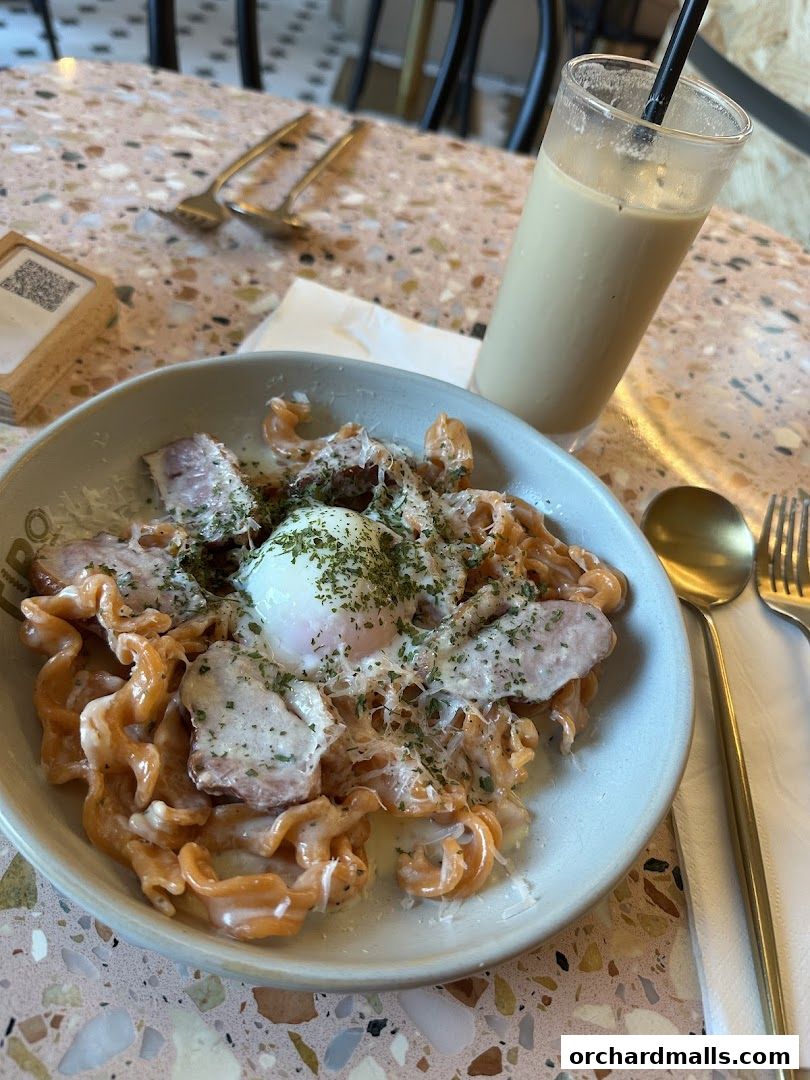 A delicious pasta dish with a poached egg and a refreshing drink on a terrazzo table.