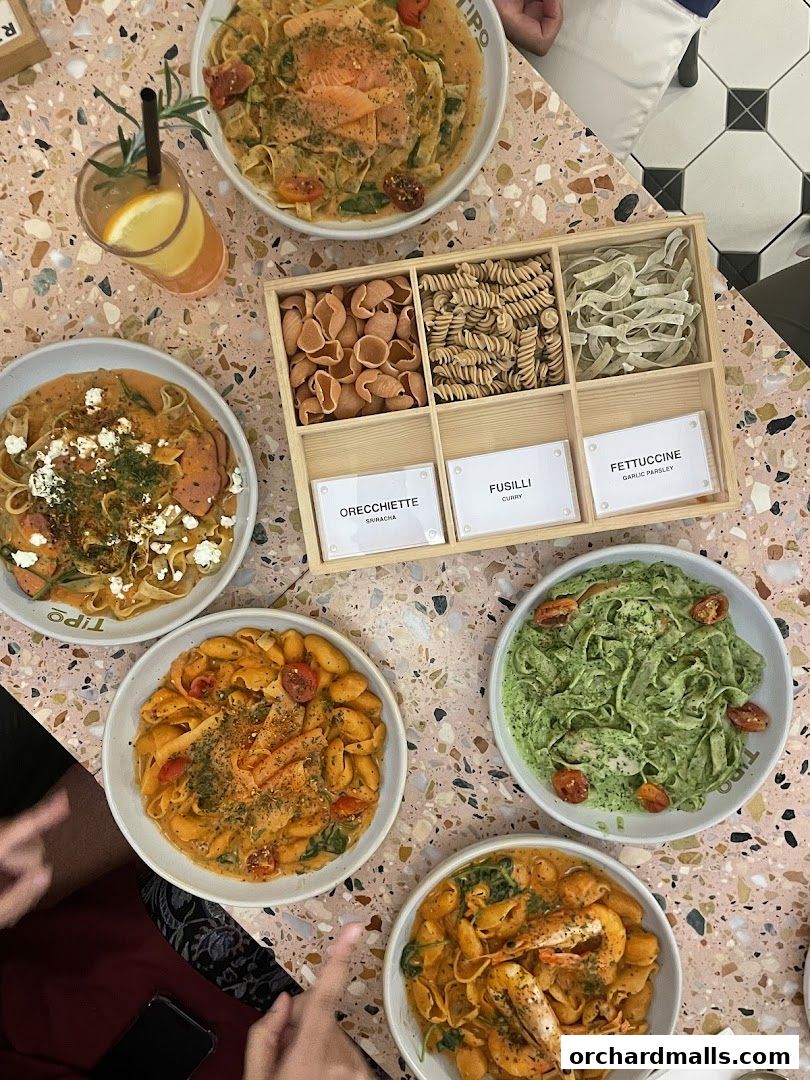 A spread of delicious pasta dishes and a selection of pasta shapes on a terrazzo table.