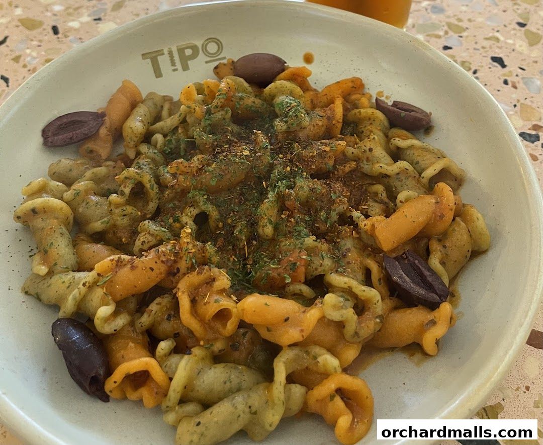 A close-up shot of a colorful pasta dish with olives and herbs.